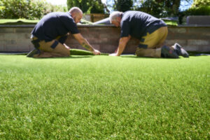Two workers making sure artificial grass fits properly